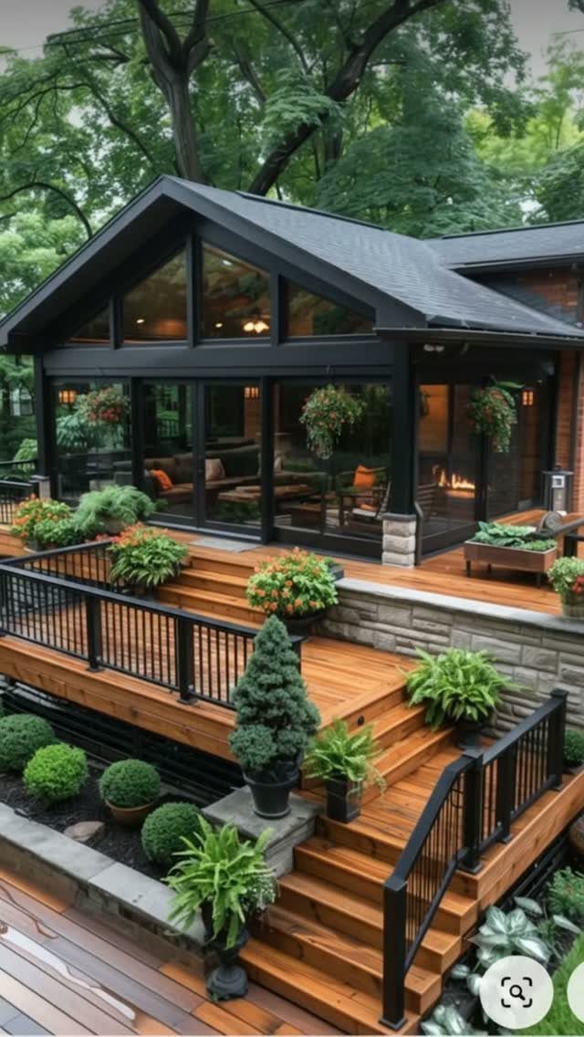 11 Around Deck Landscaping Ideas with Photos and Tips 10 Wooden deck stairs with black railings surrounded by various potted plants and lush green landscaping.