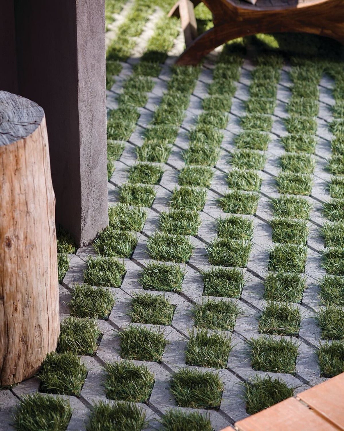 11 Around Deck Landscaping Ideas with Photos and Tips 4 Square grey stone pavers with green grass growing in the gaps between them in a checkerboard pattern.