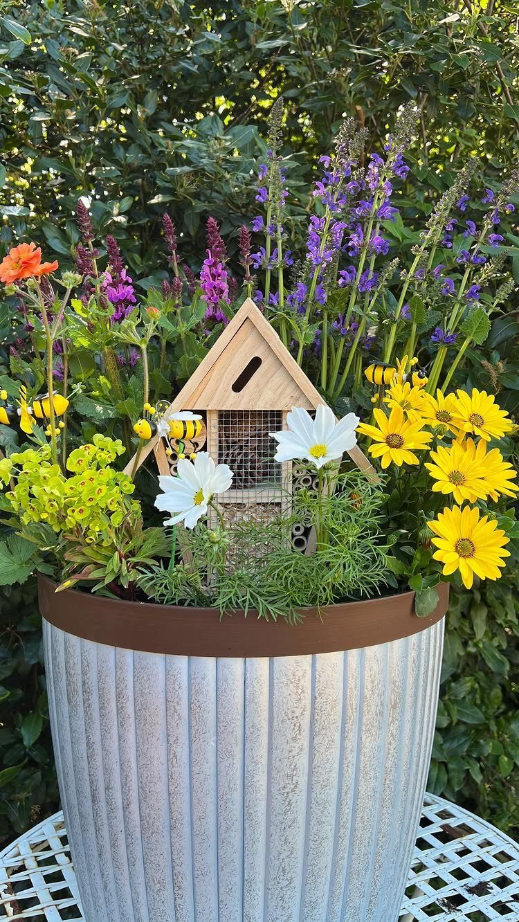 11 Around House Landscaping Ideas for Foundation to Fence 11 Colorful flowers in a metal planter featuring white cosmos, yellow sunflowers, and purple salvia.