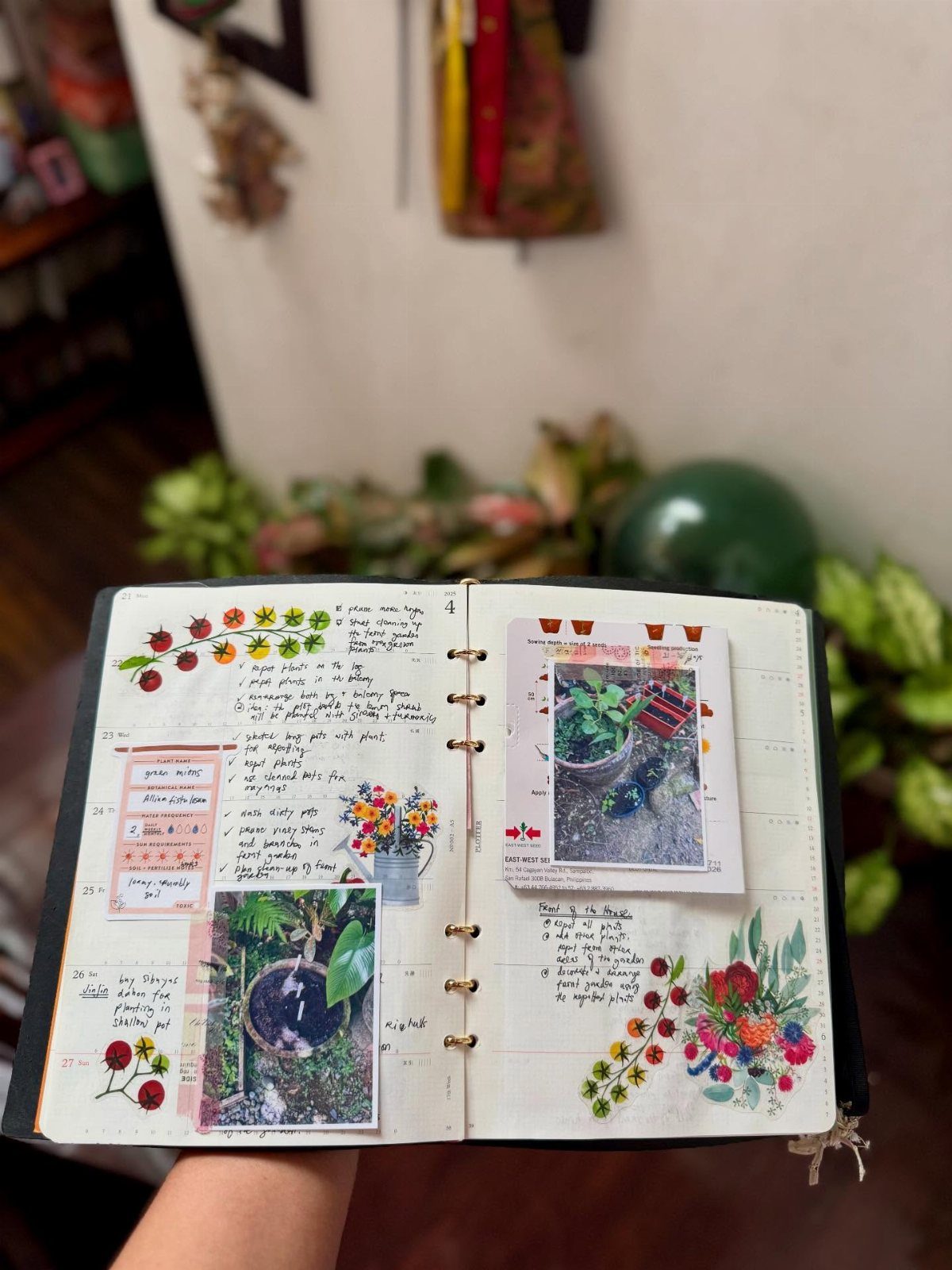 An open notebook featuring handwritten gardening notes, plant photographs, and colorful floral stickers.