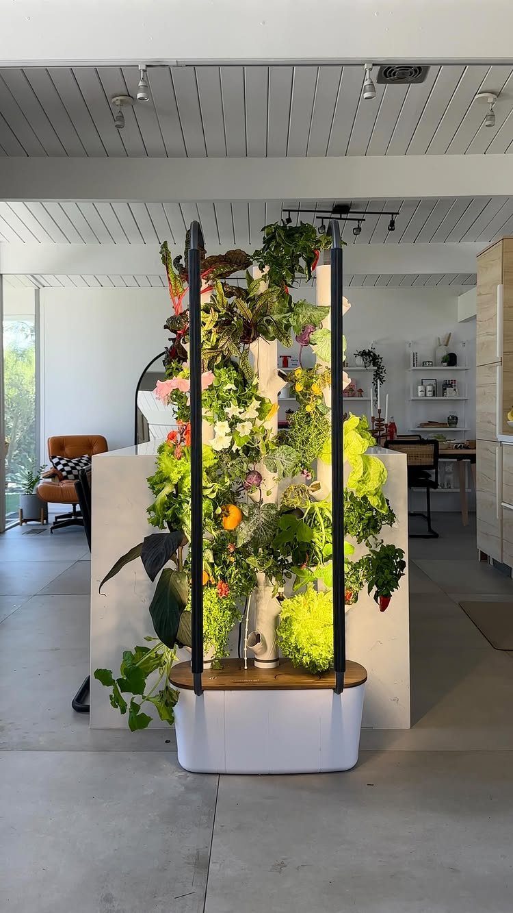 A vertical indoor garden tower overflowing with lush green plants and small flowers in a modern room.