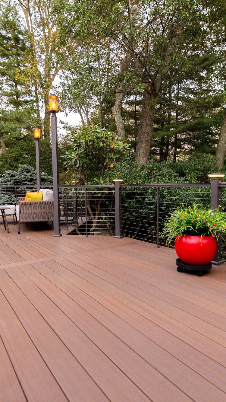 21 Backyard Deck Ideas For Any Size Space 17 Wooden deck with dark metal railings and outdoor lighting overlooking a dense green forest.