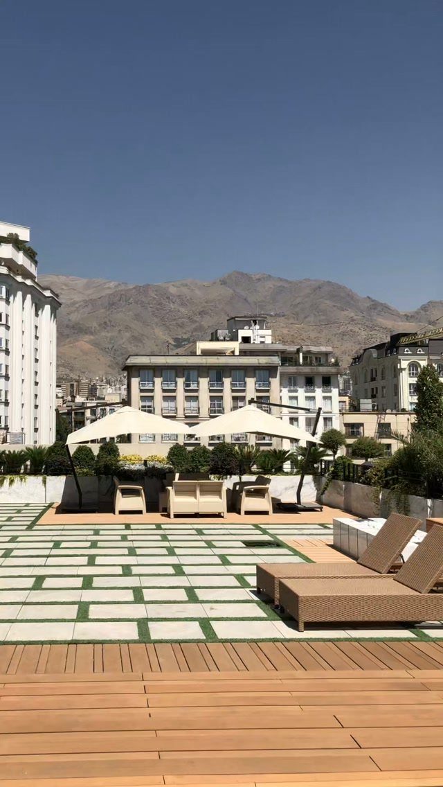 21 Backyard Deck Ideas For Any Size Space 7 Rooftop terrace with wooden decking, lounge furniture, and mountains in the background.