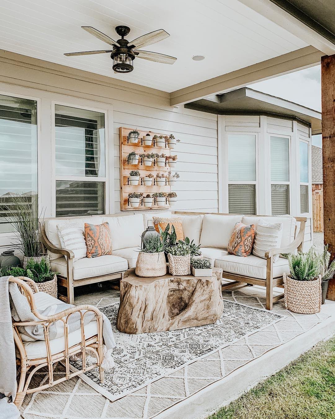A large natural tree stump coffee table placed on a patterned rug in a patio setting.