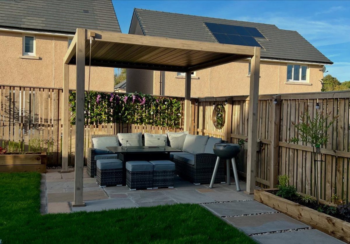 Wooden pergola covering a patio set with grey wicker furniture and a coffee table.