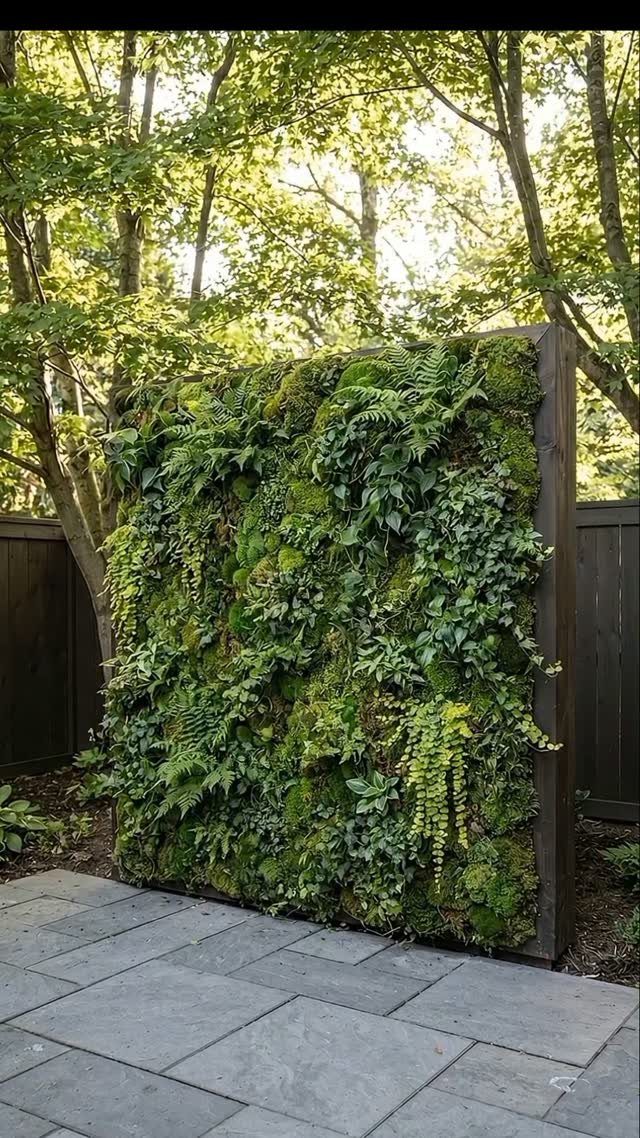 A lush green vertical garden wall with ferns and moss mounted on a wooden frame.