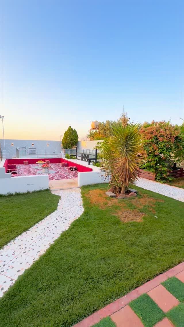 23 Backyard Garden Inspiration Ideas for Any Space 14 A sunken patio with red borders and patterned tiles surrounded by a green lawn.