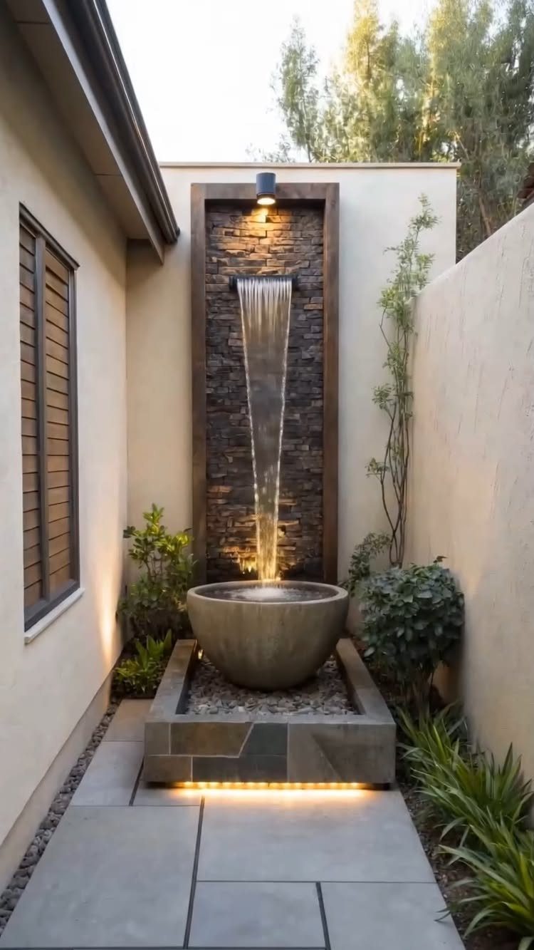 23 Backyard Garden Inspiration Ideas for Any Space 10 A modern stone water feature with a cascading waterfall into a large bowl in a courtyard.