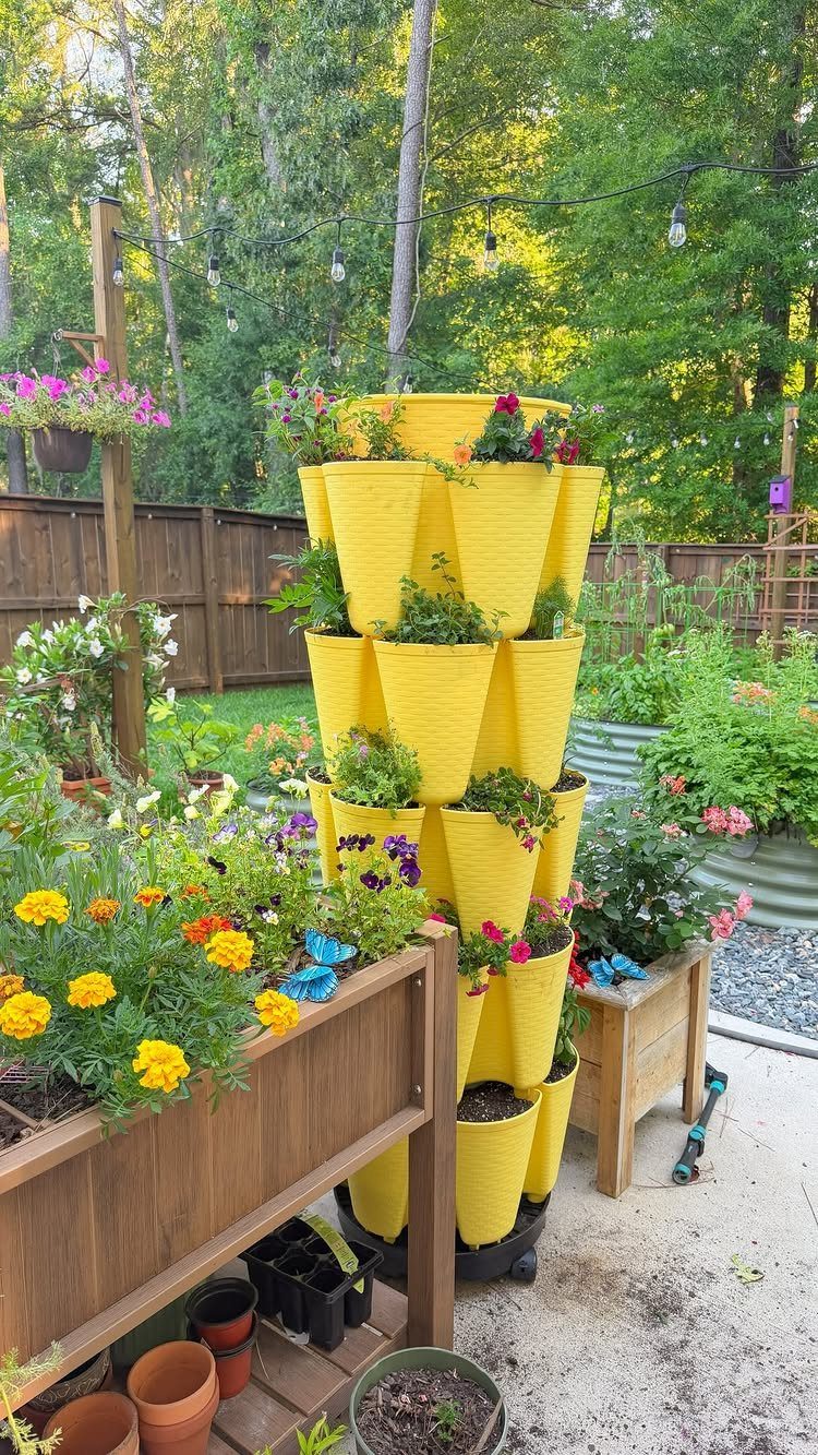 9 Backyard Patio Ideas with Fire Pits, Shade Sails & Retractable Awnings 7 Yellow vertical planters filled with colorful flowers and greenery in a backyard garden setting.