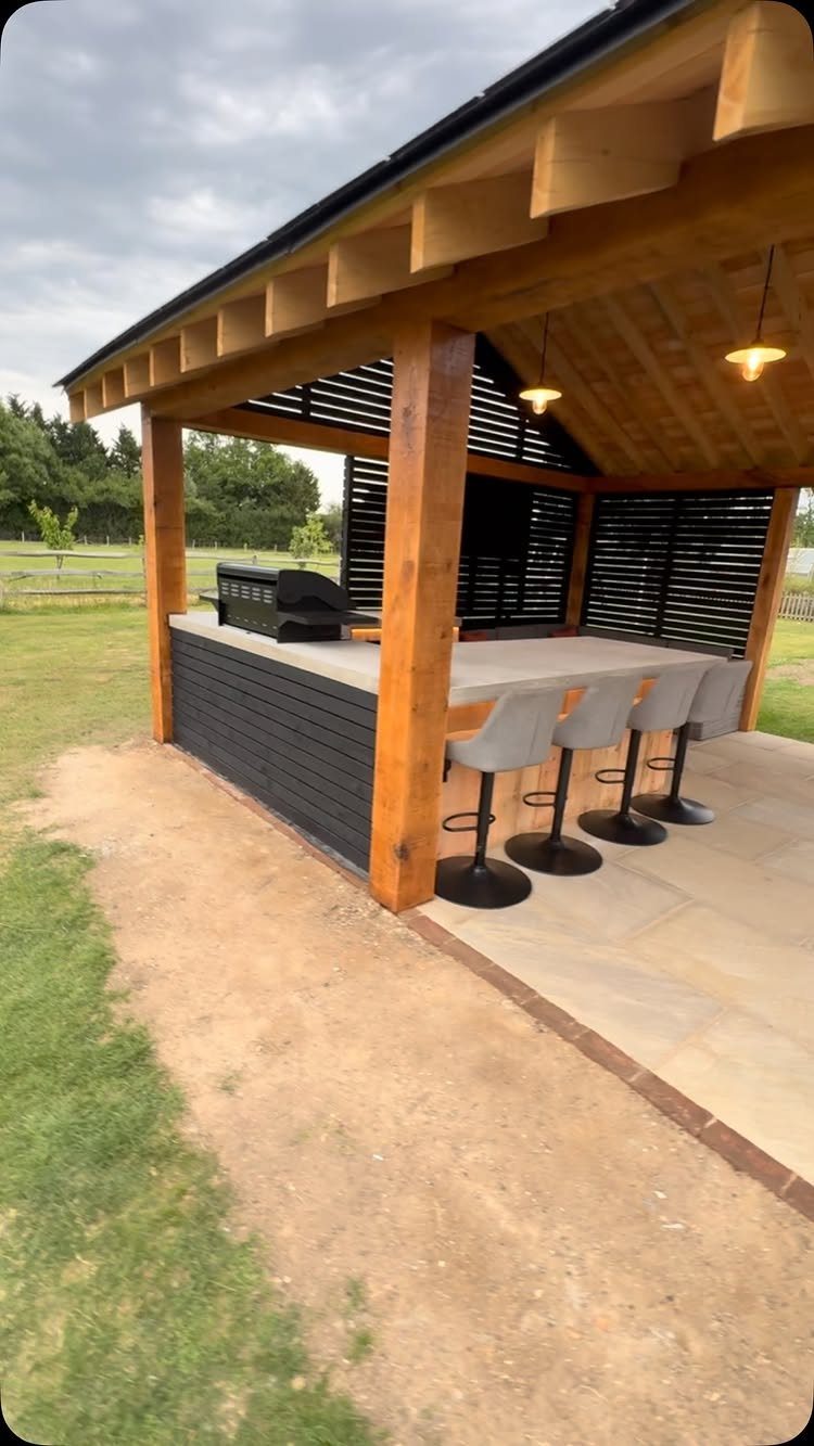 Wooden gazebo featuring a built-in outdoor kitchen with a grill and bar seating.