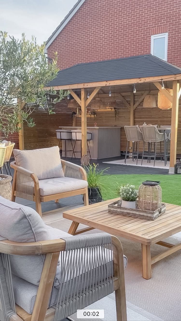 Wooden gazebo featuring a built-in bar with stools and outdoor lounge furniture on a patio.