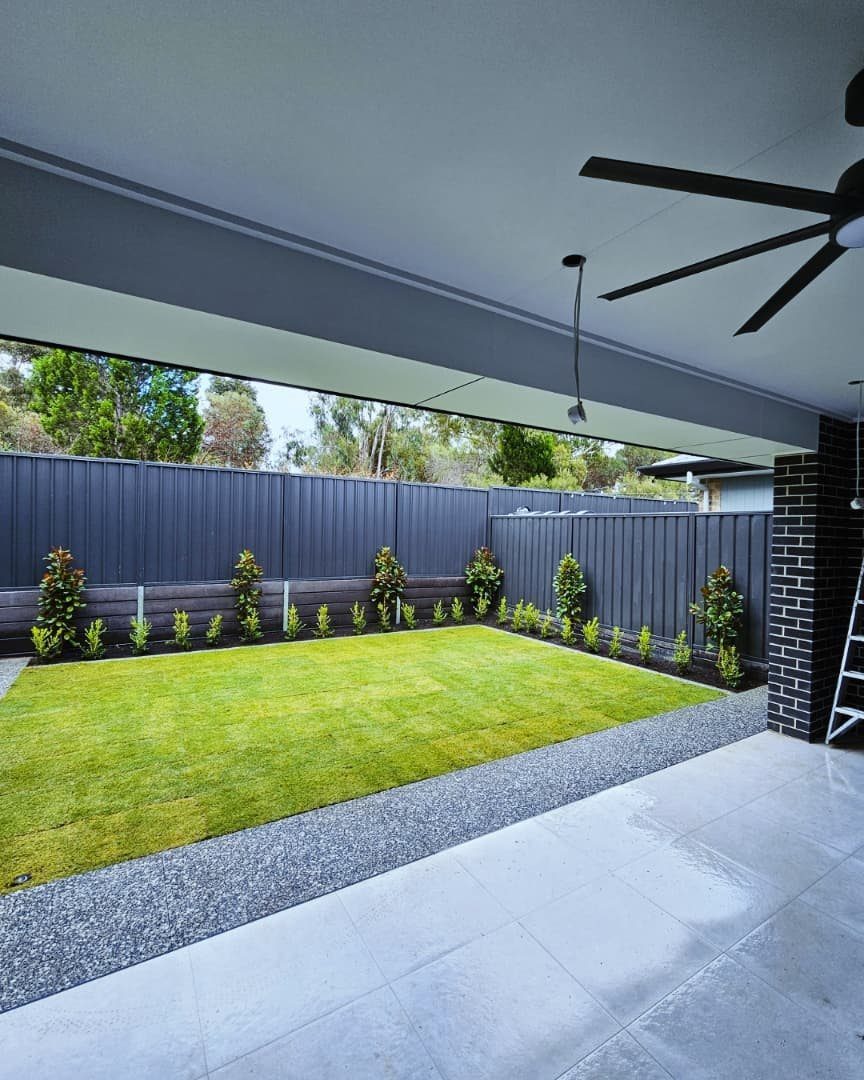 16 Beautiful Backyard Ideas for Cozy to Elegant Outdoor Spaces 10 A neat green lawn with a gravel border and small shrubs against a dark fence.