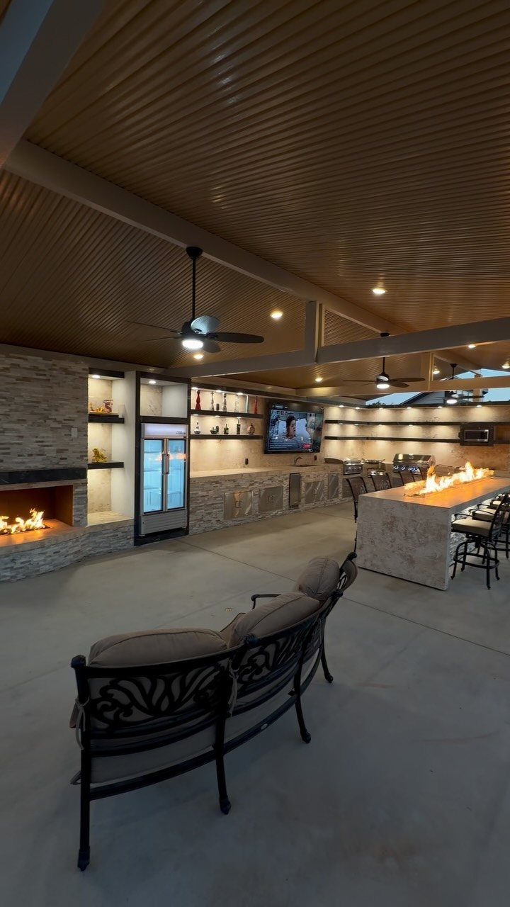 16 Beautiful Backyard Ideas for Cozy to Elegant Outdoor Spaces 9 Modern outdoor living area with a stone bar featuring flames and a large fireplace.