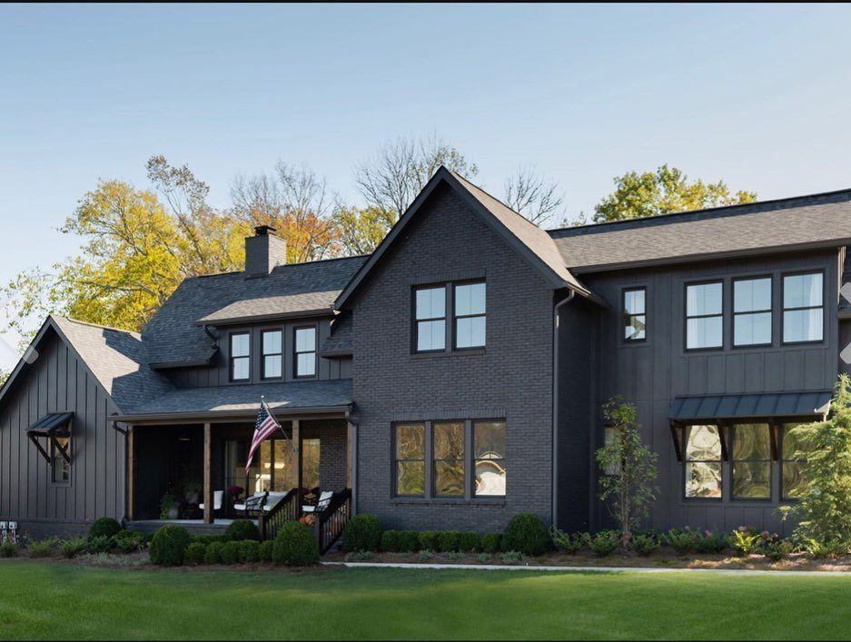 16 Black Modern Farmhouse Exterior Ideas With Photos 4 A large modern farmhouse featuring dark black painted brick walls and black window frames.