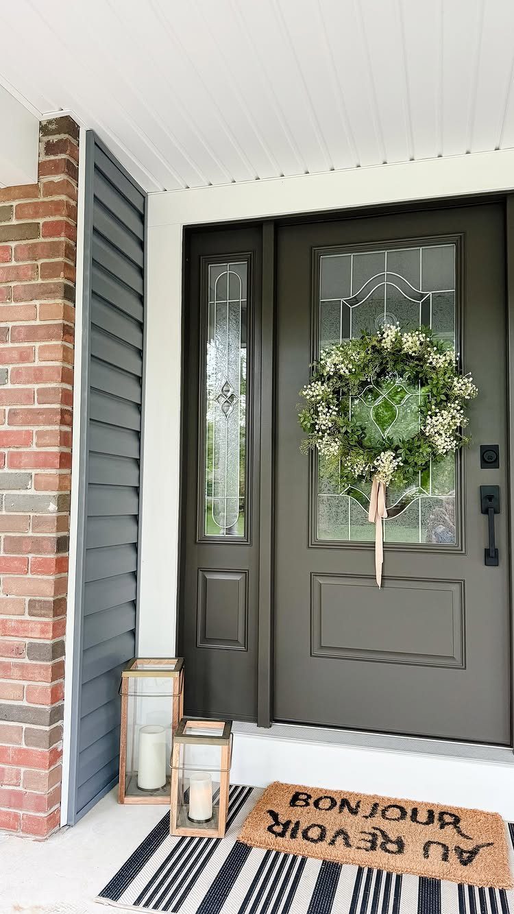 16 Black Modern Farmhouse Exterior Ideas With Photos 8 Dark grey farmhouse front door featuring a green wreath and glass window panels.