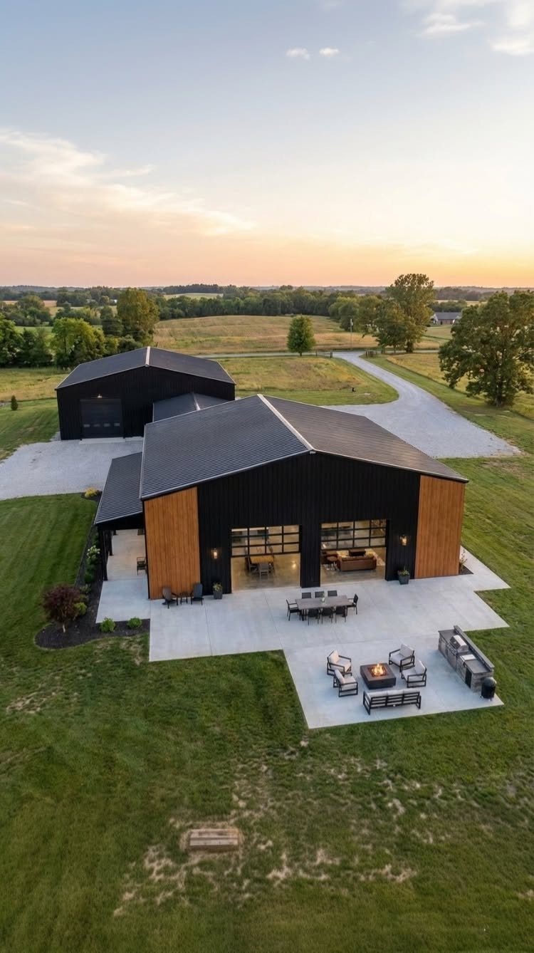 16 Black Modern Farmhouse Exterior Ideas With Photos 16 Modern black farmhouse with wood siding and a large concrete patio under a sunset sky.