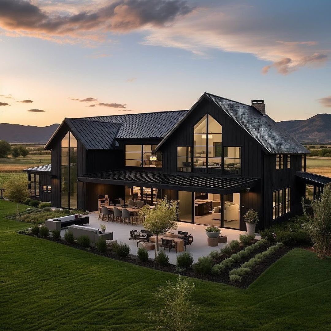 16 Black Modern Farmhouse Exterior Ideas With Photos 3 Black modern farmhouse with a large patio, outdoor furniture, and lush green landscaping at sunset.