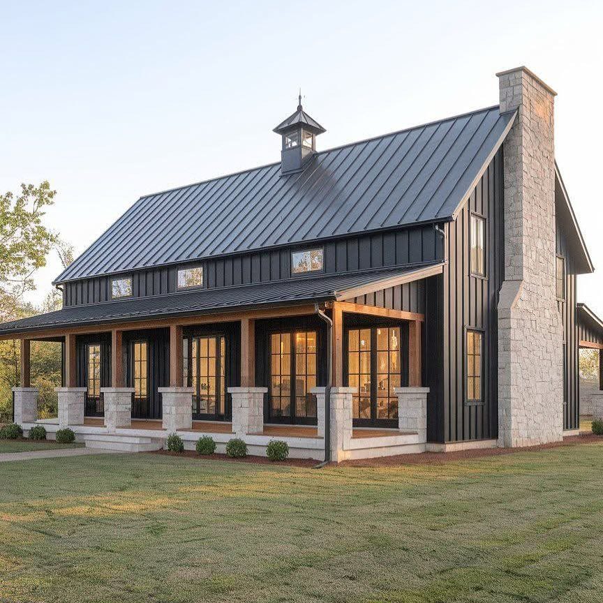 16 Black Modern Farmhouse Exterior Ideas With Photos 15 Black modern farmhouse with a metal roof, stone chimney, and a large wooden front porch.