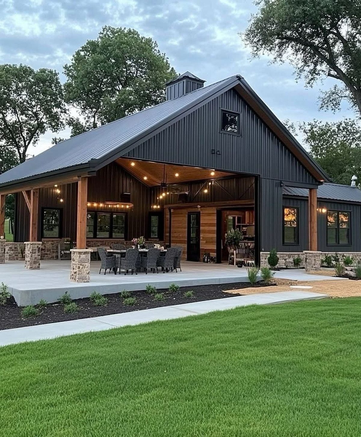 16 Black Modern Farmhouse Exterior Ideas With Photos 11 Black modern farmhouse with a large covered patio, wooden posts, and a dark metal roof.
