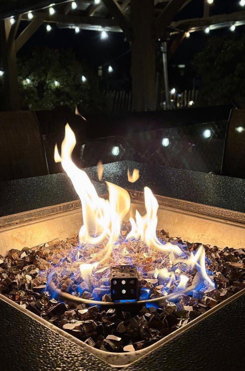 Flames rising from a square fire pit filled with dark decorative fire glass.