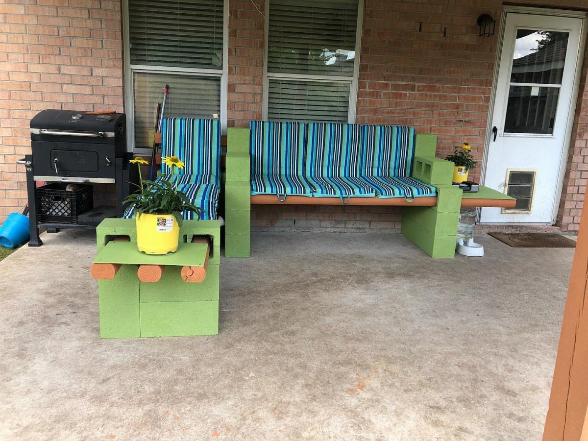 Green cinder block outdoor furniture with blue striped cushions sits on a concrete patio.