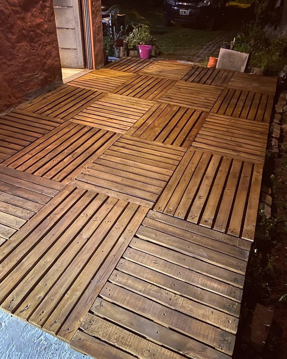 Wooden pallets arranged in a grid to create a DIY backyard patio surface.