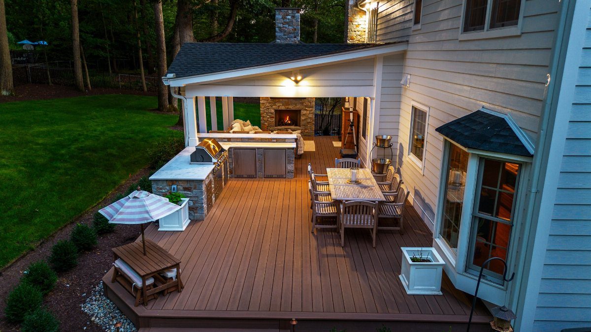 12 Deck Furniture Ideas: Layouts for Seating, Dining & Entertaining 3 Wooden deck featuring an outdoor kitchen, dining set, and a fireplace lounge area.