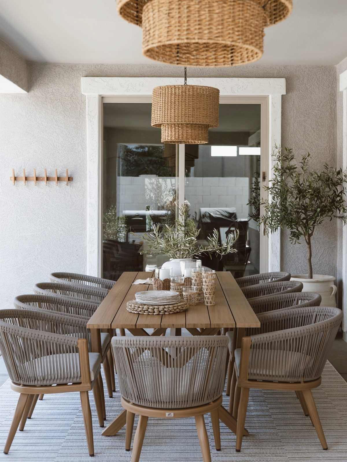 12 Deck Furniture Ideas: Layouts for Seating, Dining & Entertaining 2 A long wooden dining table with eight grey rope chairs arranged on an outdoor patio.