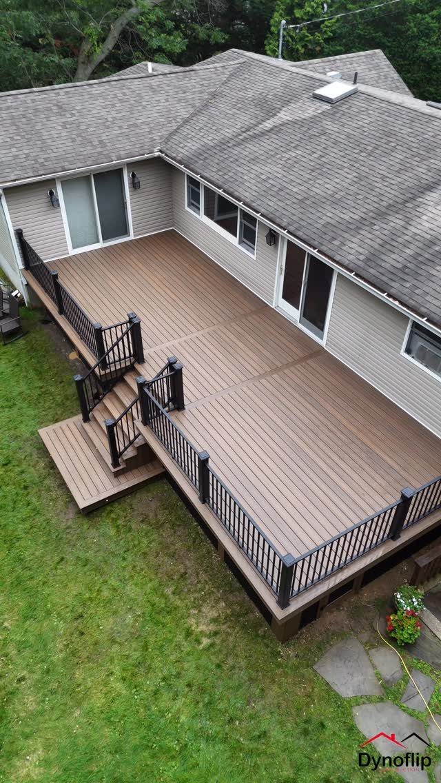 15 Decks and Porches Back Patio Ideas for Outdoor Living 11 A large brown wooden deck with black railings attached to the back of a house.