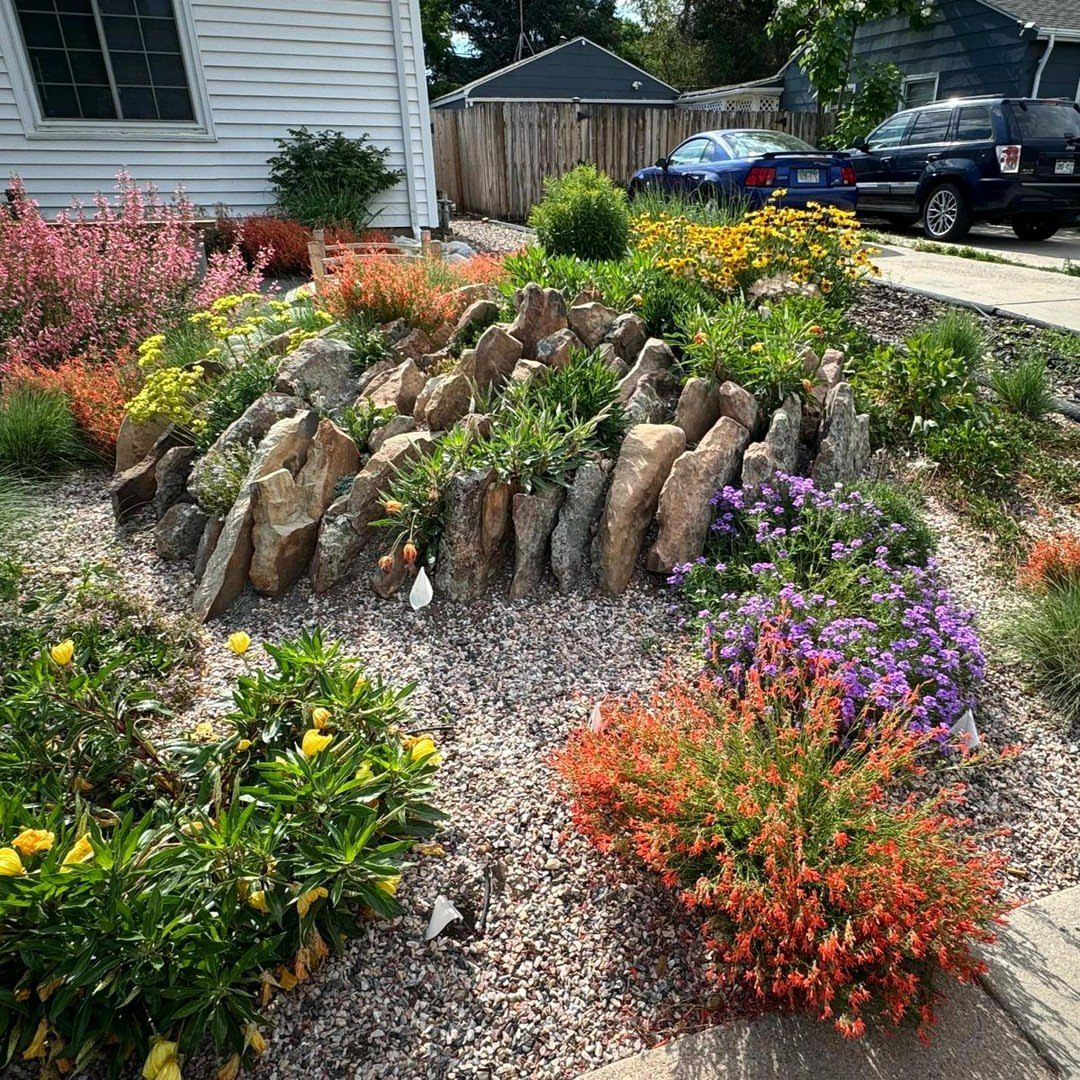 19 DIY Landscaping Ideas on a Budget for Any Yard 2 Large upright stones arranged in a gravel bed surrounded by colorful flowering plants.