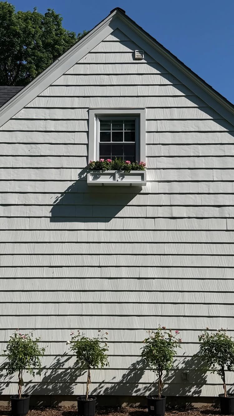 19 DIY Landscaping Ideas on a Budget for Any Yard 19 A white window box with pink flowers sits beneath a window on a shingle house.
