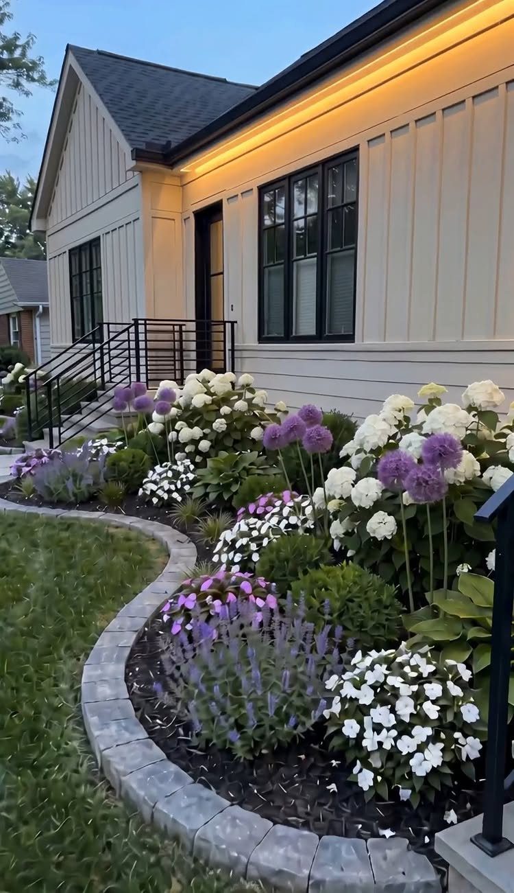 19 DIY Landscaping Ideas on a Budget for Any Yard 14 White hydrangeas and purple alliums blooming in a landscaped flower bed with stone edging.