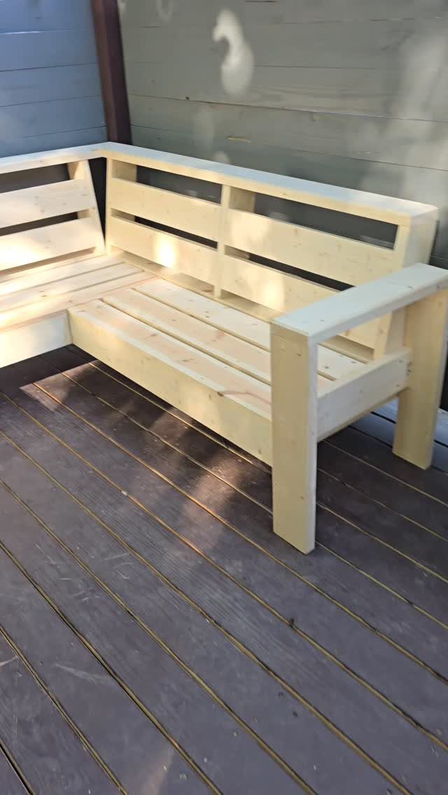 Unfinished light wood L-shaped sectional sofa sitting on a dark wooden outdoor deck.