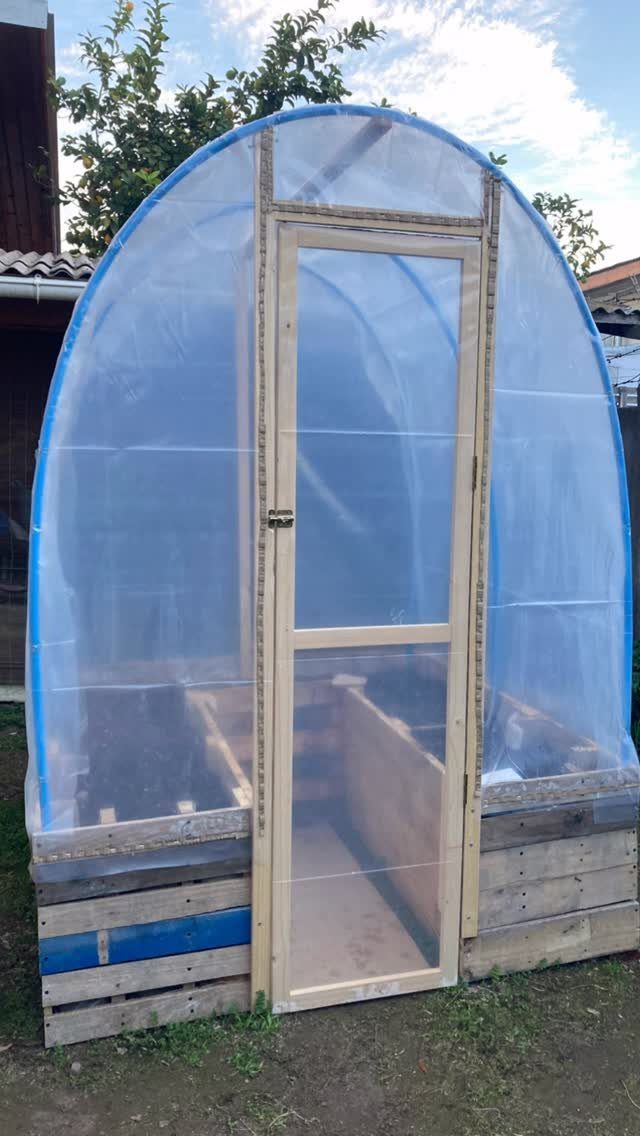 Greenhouse Using Pallets: 5 Builds for Small Yards 5 Small arched greenhouse with a translucent plastic cover and a base made from wooden pallets.