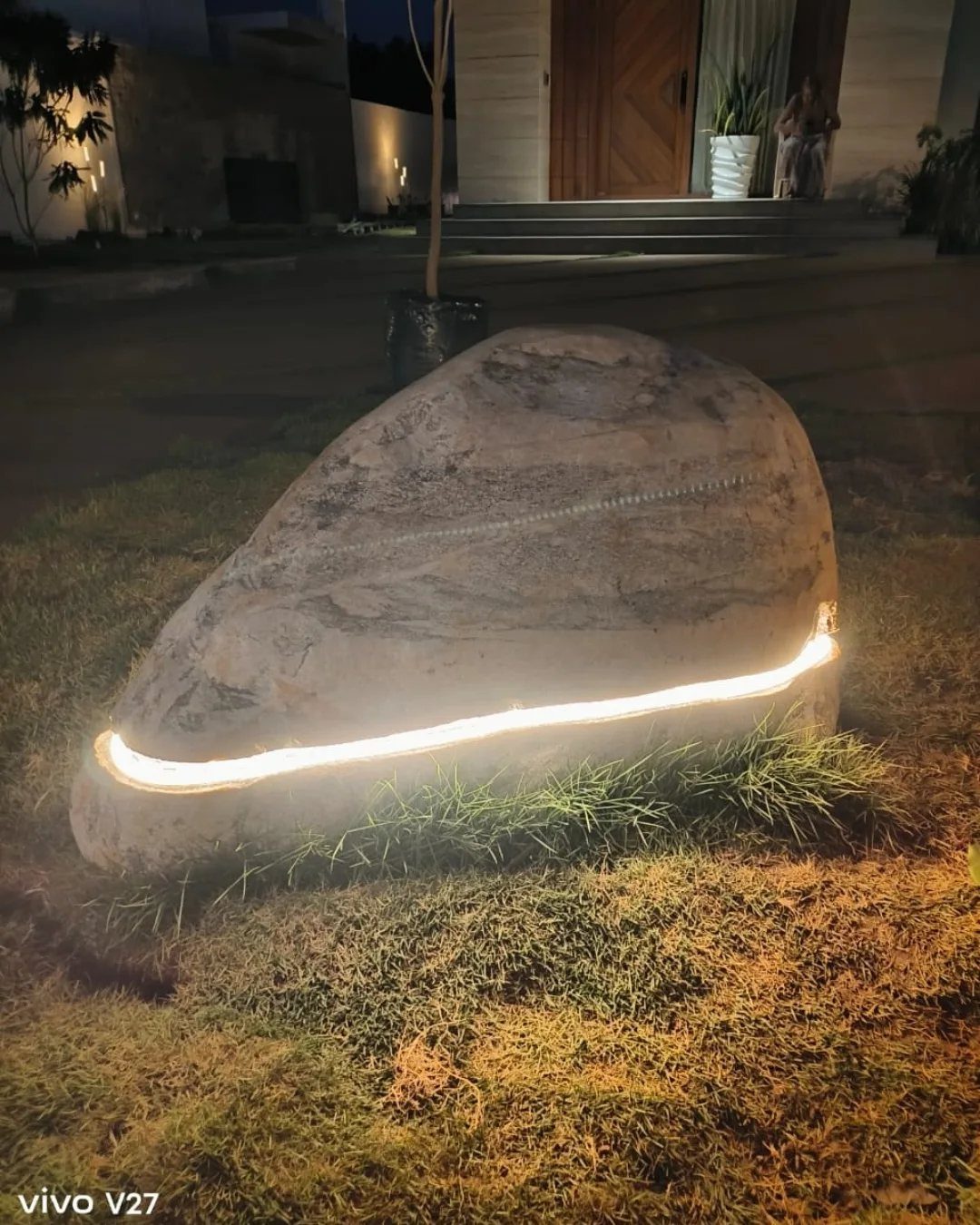 A large boulder illuminated by a glowing LED light strip embedded in its base.