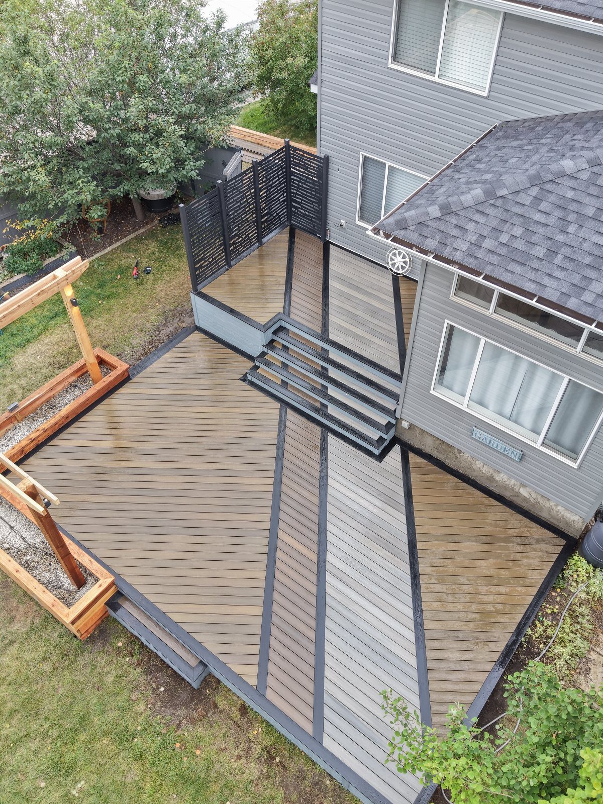 An aerial view of a multi-level deck with alternating light brown and dark grey boards.