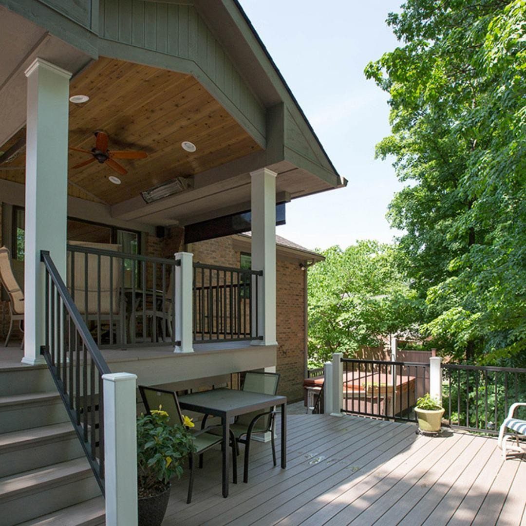Multi-level wooden deck with a dining table below and a covered seating area above with a ceiling fan.