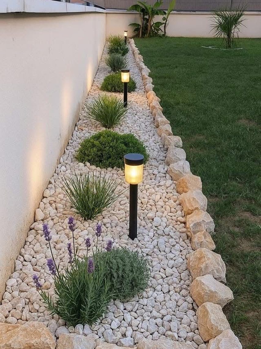 16 Small Home Landscaping Ideas That Fit Any Plot 5 Small green shrubs and lavender plants growing in a white gravel garden bed with solar lights.