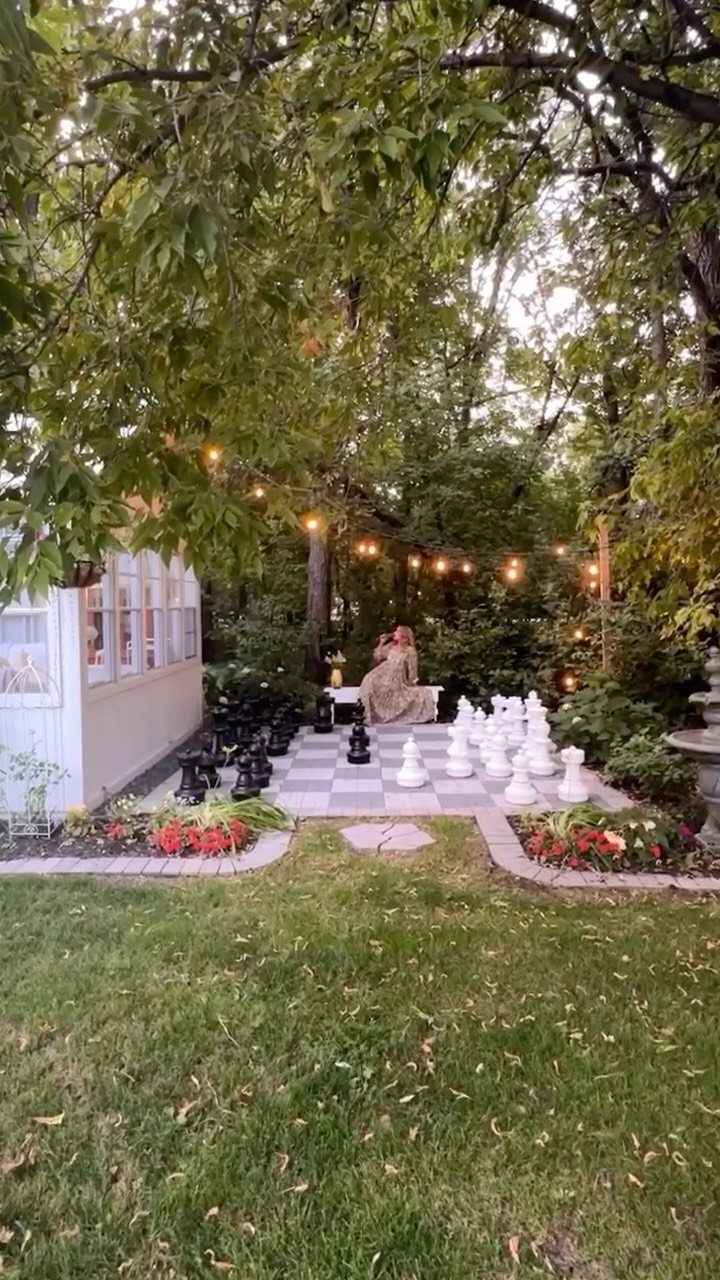 16 Small Home Landscaping Ideas That Fit Any Plot 11 Large black and white chess pieces arranged on an outdoor checkered patio surrounded by greenery.