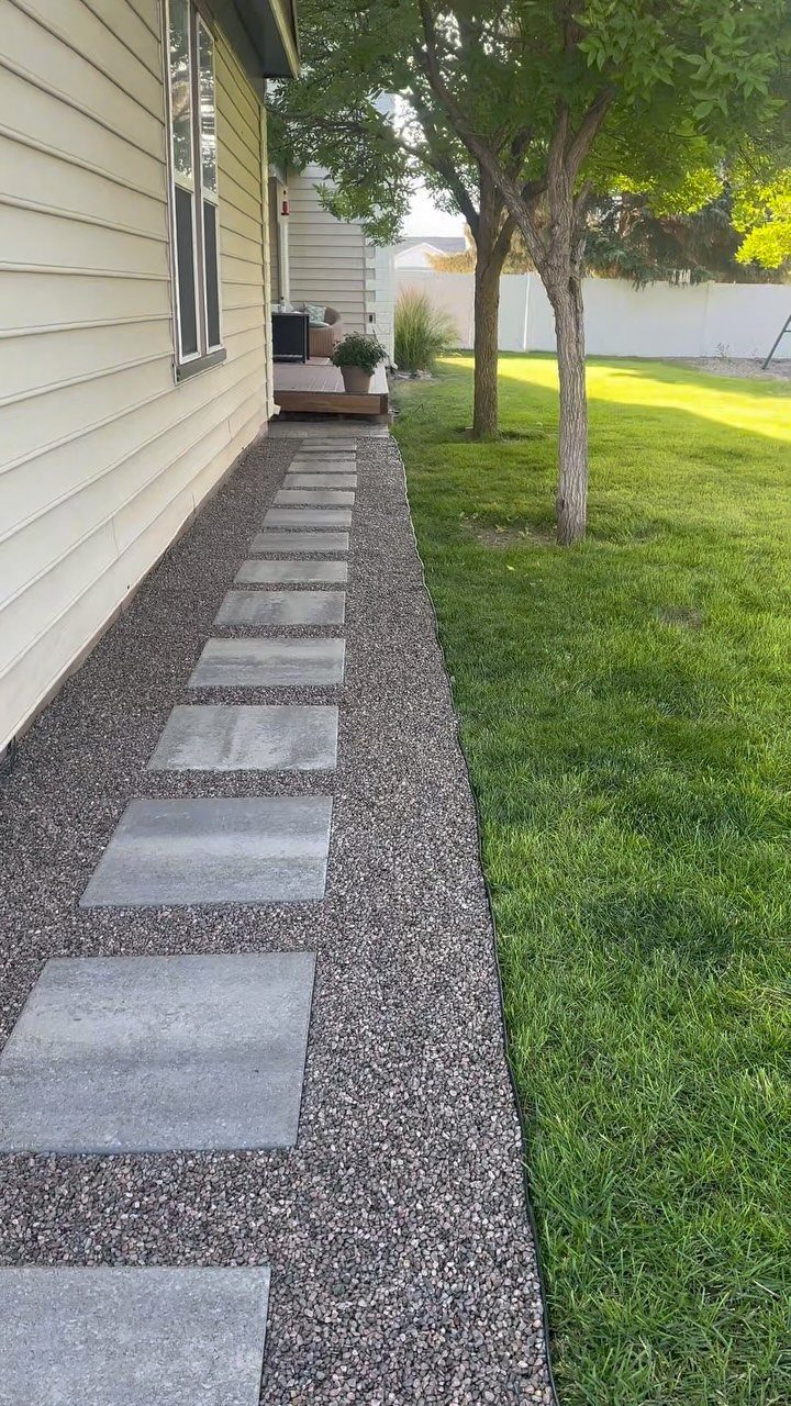 16 Small Home Landscaping Ideas That Fit Any Plot 6 Grey rectangular stepping stones set into a gravel path alongside a green lawn and house.